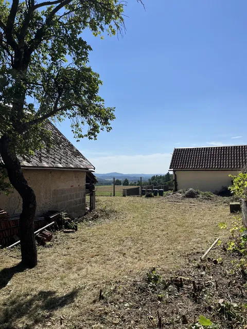 Stejné místo po posekání — čistý trávník až k sousednímu domu, v pozadí výhled do kraje